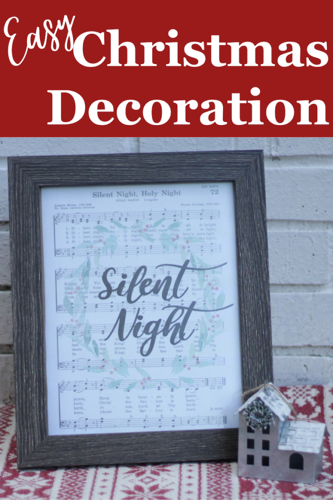 pinnable graphic with white text saying "easy Christmas Decoration" over a red background above a photo of a wooden frame with Silent night sheet music inside displaying a Christmas wreath and script text of silent night in the center, beside a metal house decor on top of red and cream Christmas designed fabric 