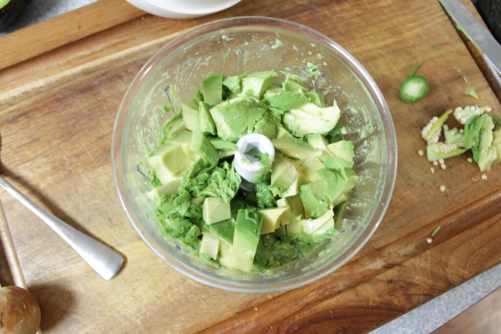 Diced avocado added to food processor along with other guacamole ingredients