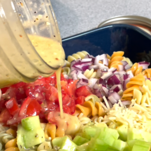 pouring dressing onto pasta salad