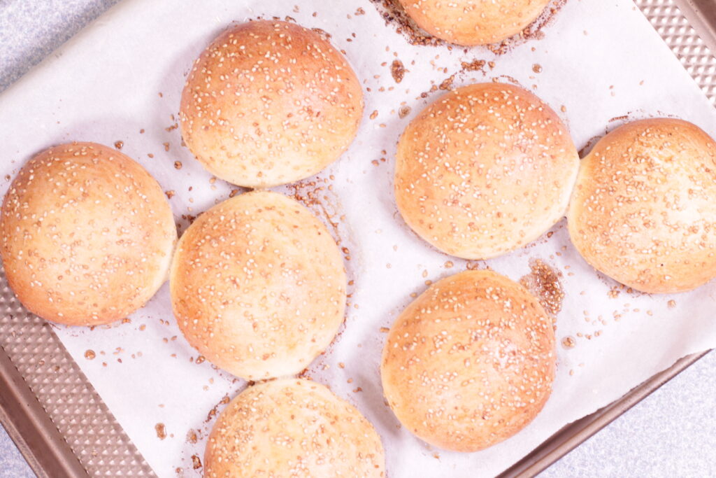 hamburger buns on parchment paper on baking sheet