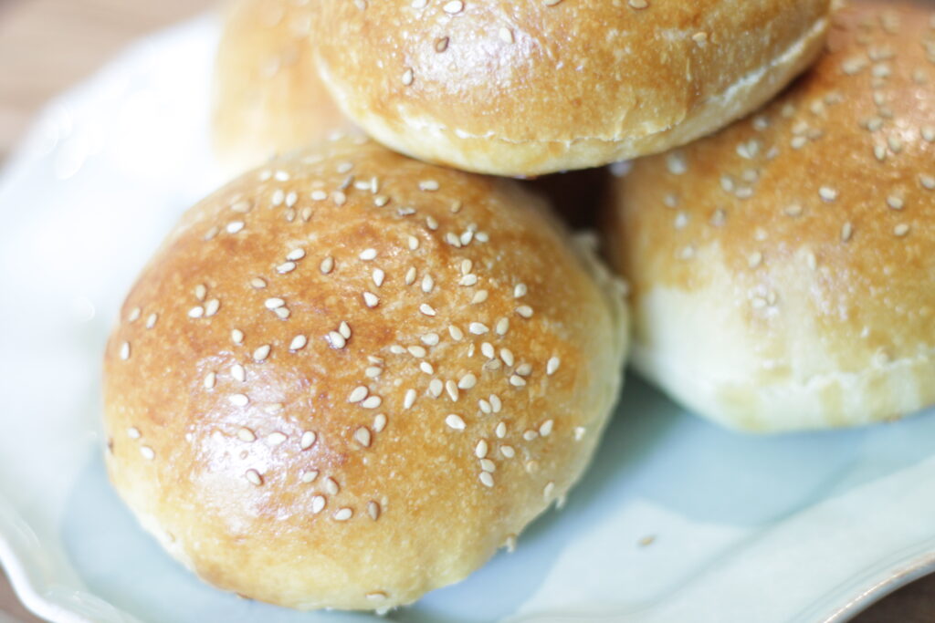 sesame seed hamburger buns sitting on blue plate