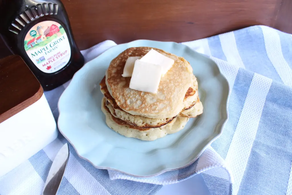 stack of sourdough pancakes with pads of butter on a blue plate
