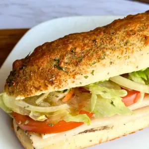 potato flake sourdough Italian herb and cheese bread on a white plate used for a cold sandwich
