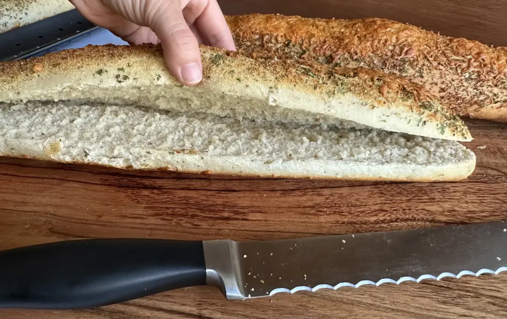 hand lifting up the top of the bread after slicing with a bread knife