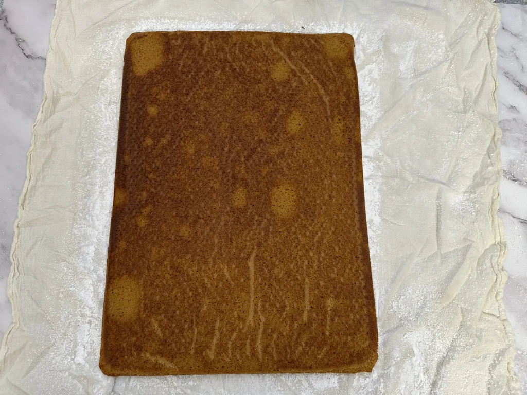 pumpkin roll cake on dusted kitchen towel