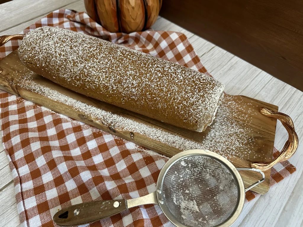 dusting pumpkin roll with powdered sugar 