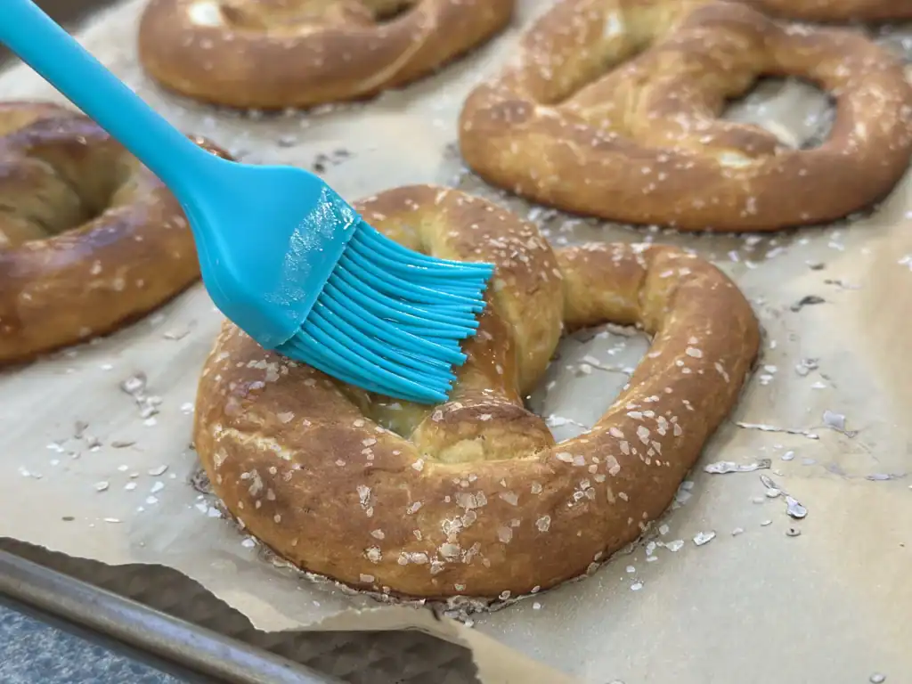 brushing potato flake sourdough pretzel with butter